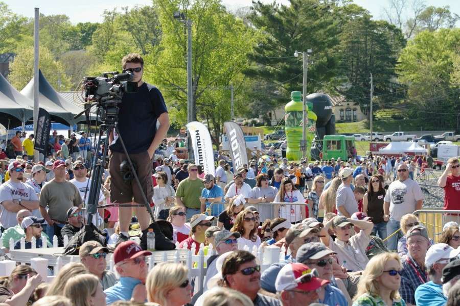 A cameraman stands on a platform above the crowd.