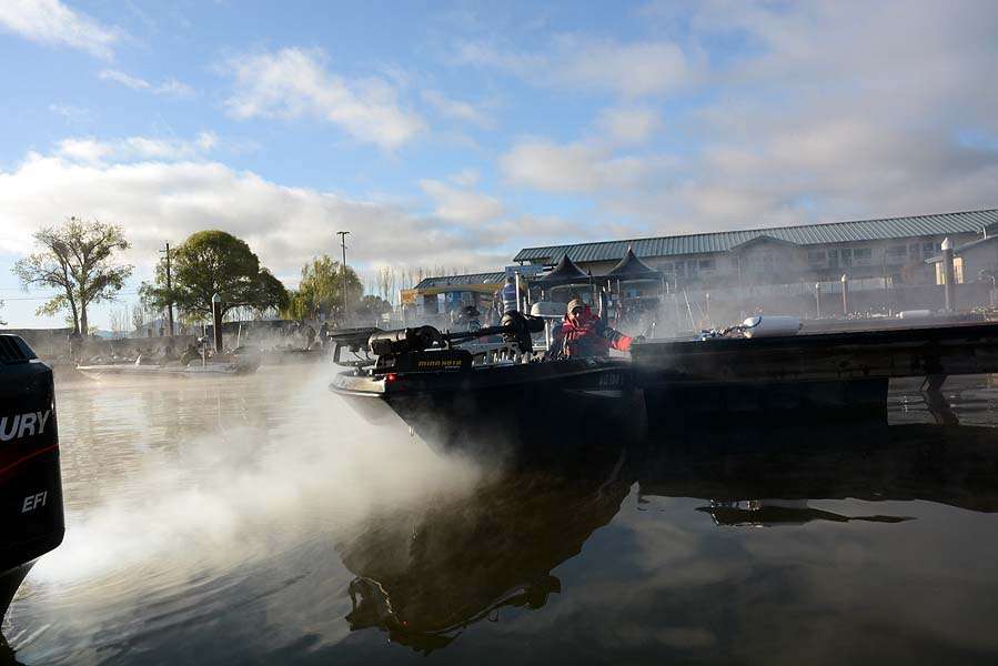 The chilly air sends damp mist from the exhausts of the outboards as the boats move through the takeoff line. 