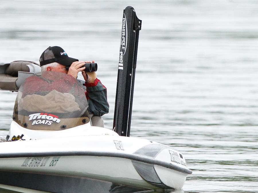 A spectator looks on with binoculars and watches how one of the best sight fisherman on tour does his work. 
