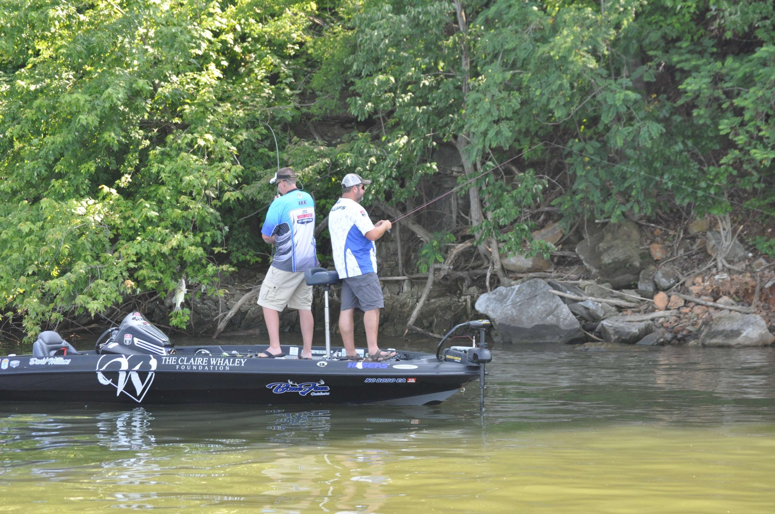 Lee swings a bass in the boat as Williams continues to cast toward the bank.