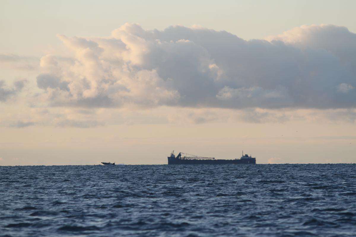 A large freighter headed north with an angler headed in the same general direction.