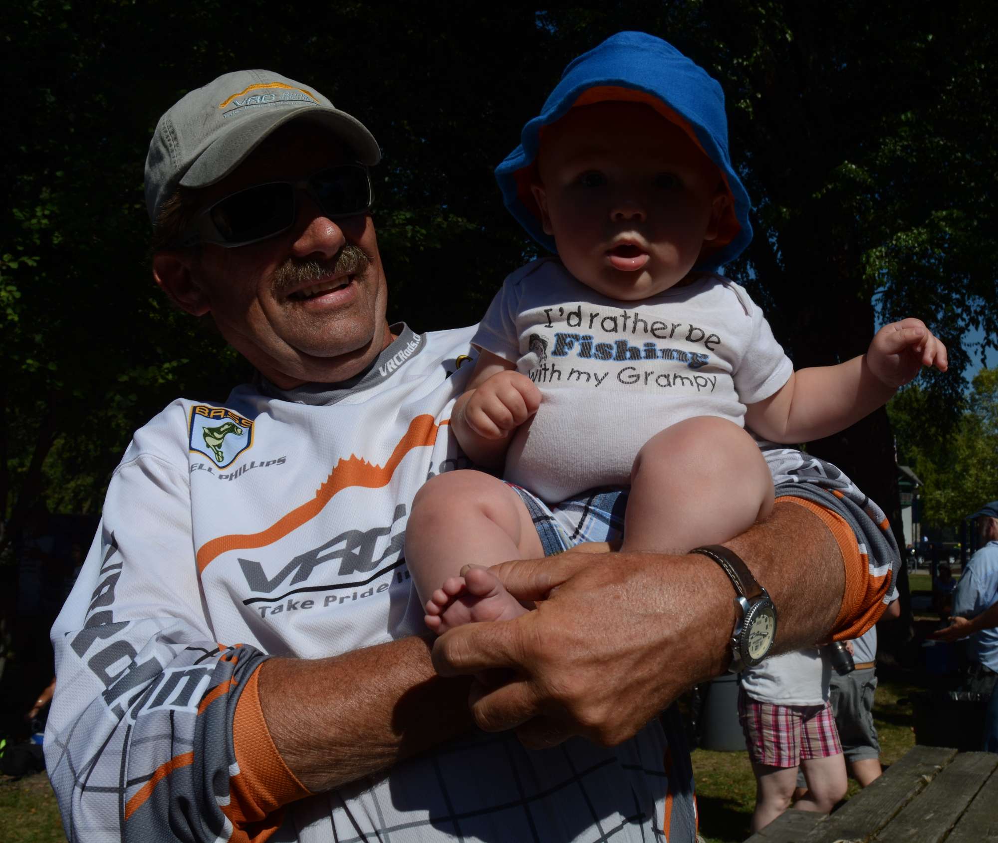 Russell Phillips holds his grandson, Charlie, whose shirt says he'd rather be fishing with his grandpa.