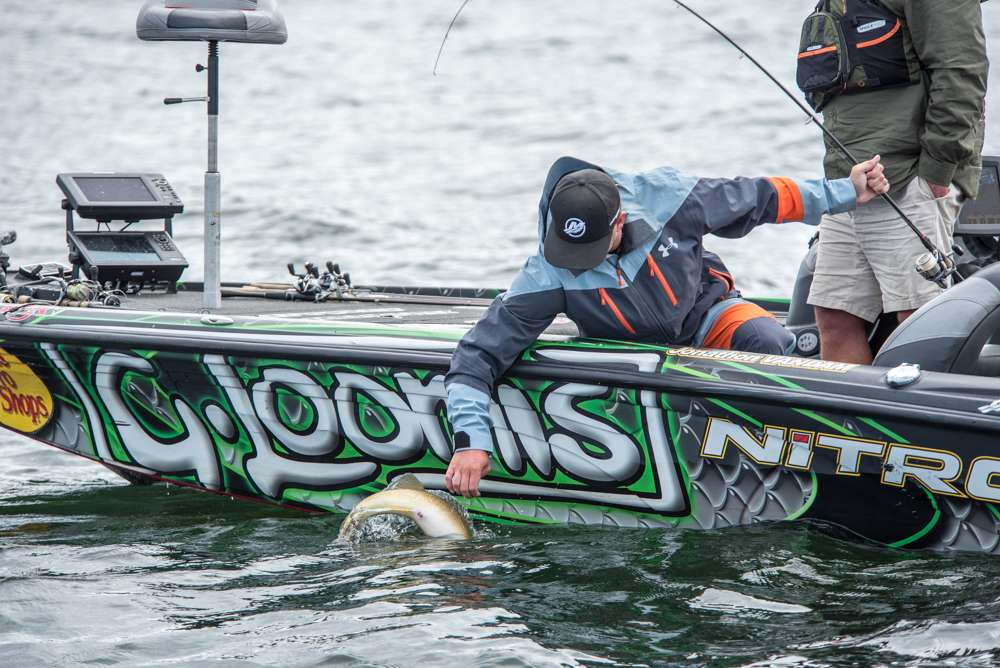 JVD reaches down to grab the fish and unhook it. 