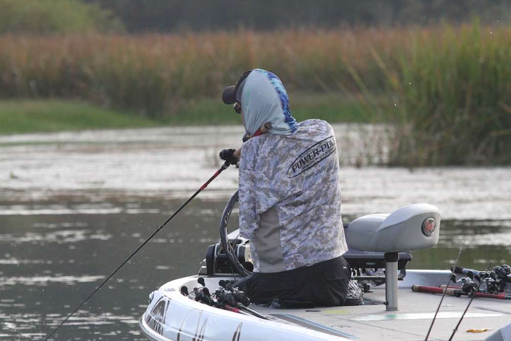 Dyer works a frog to the boat, holding his rod between his cheek and his shoulder...