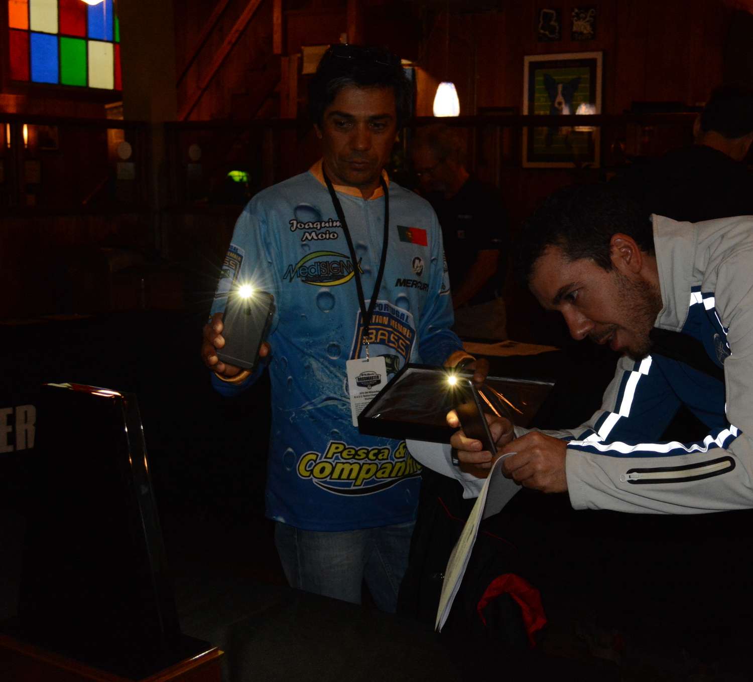 Joaquim Moio and Jose Moreira of Portugal pull out their cell phones to take photos of the championship trophy.