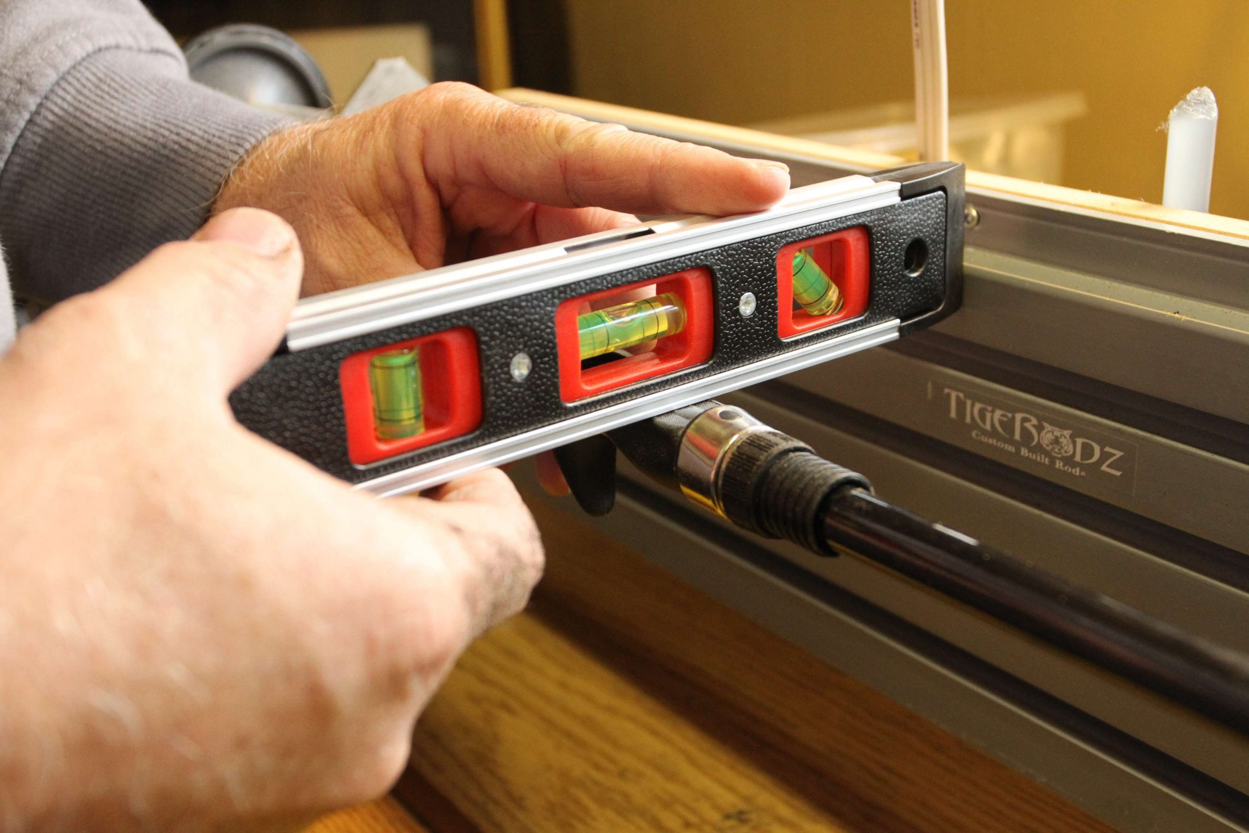 The rod is then placed back on the wrapping machine and he levels the reel seat perpendicular to the spline, which is marked by the white line just to the right of the level. 