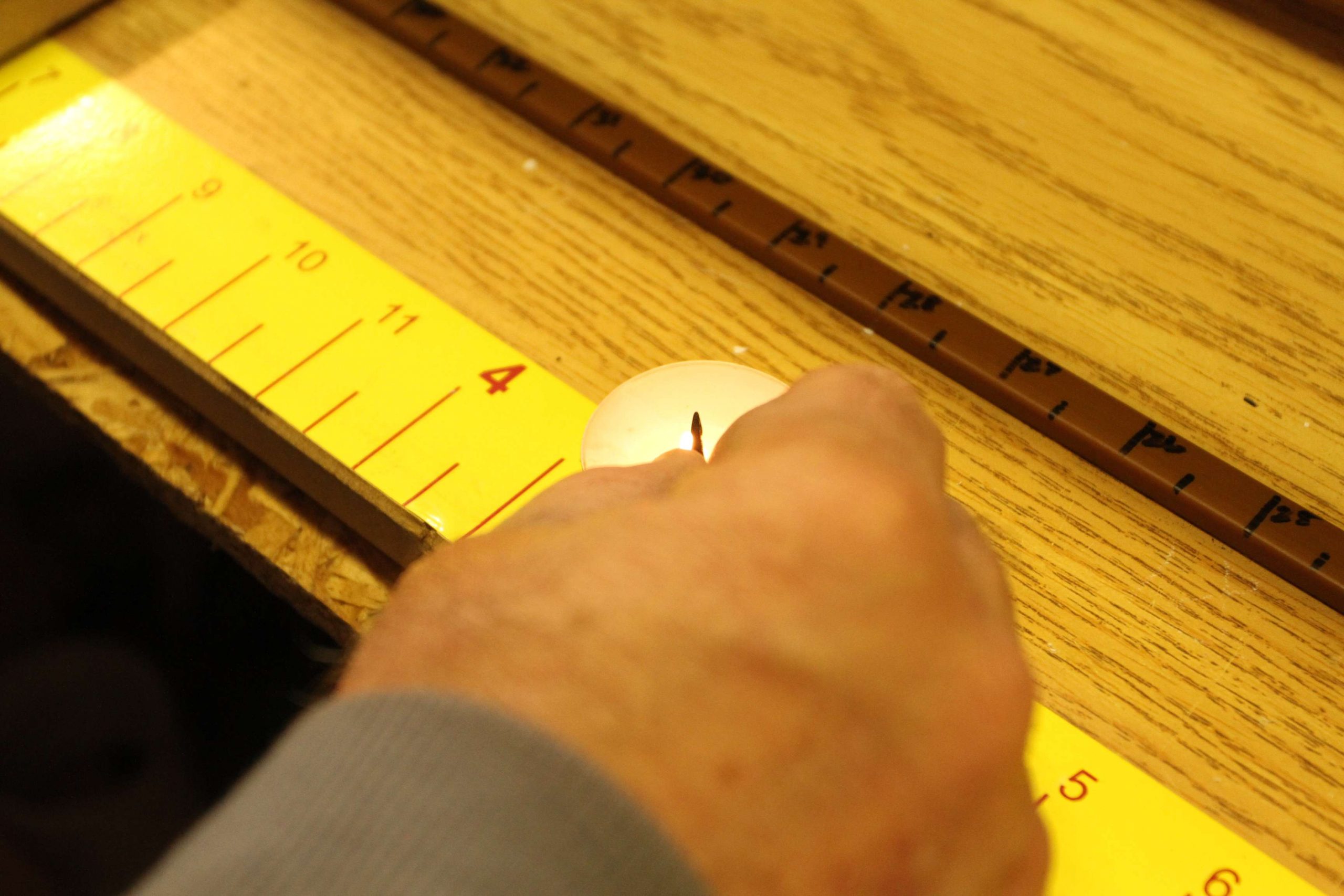 After he rod grip has cured for 24 hours, he begins the tying process. Dobbins uses hot glue to attach each guide at a previously marked location along the blank's spline. A small candle is lit, and he quickly heats the line guide in the flame before touching it to a glue stick that sits directly above the wrapping machine. 