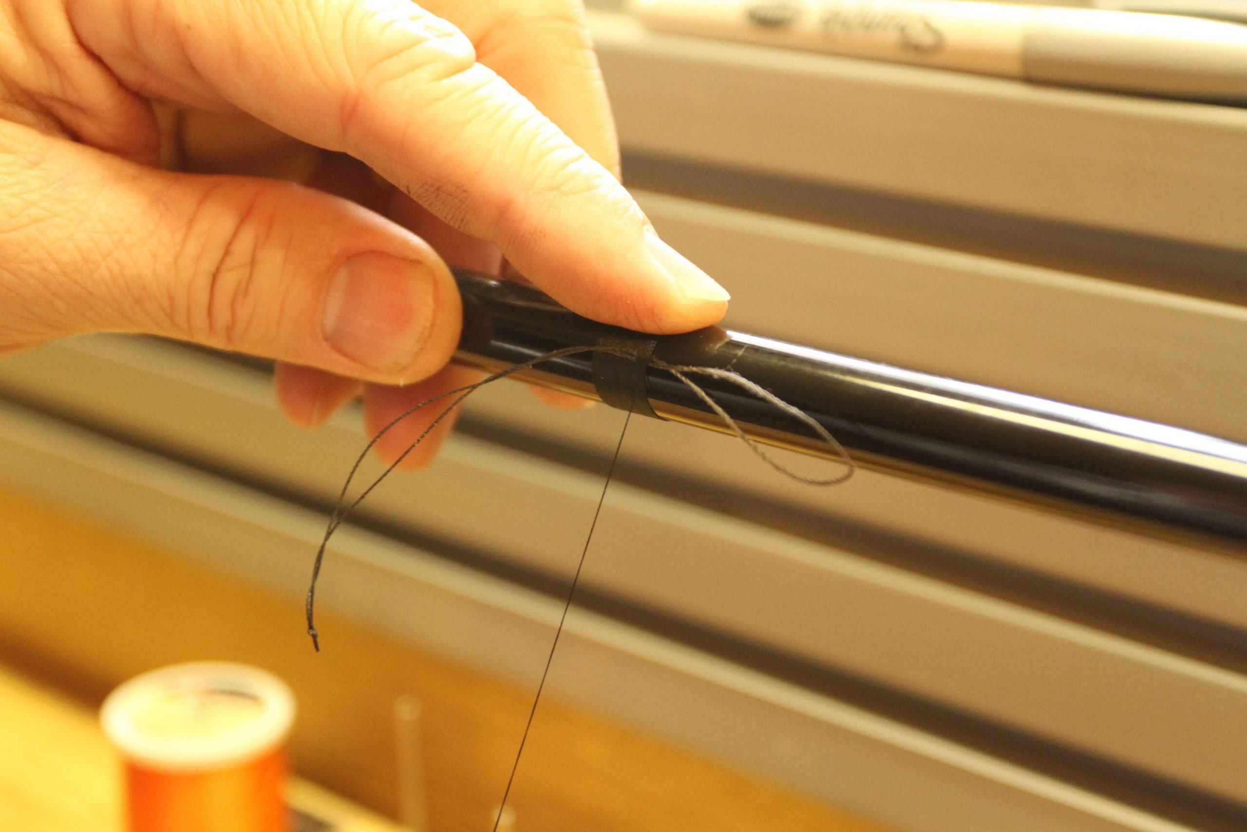 As he finishes the wrapping, he temporarily ties in a looped piece of thread. The loop on the right-hand side of this image is where you'll insert the tag end once cut from the bobbin. Pull the temporary loop towards the butt end of the rod and snug up the thread. 
