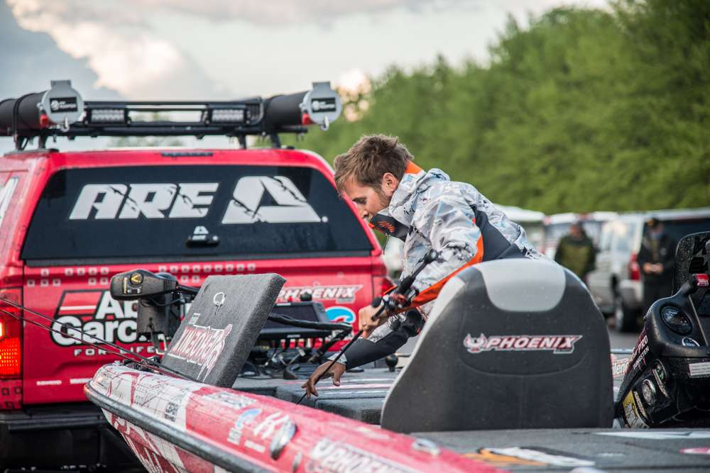 A.R.E . pro Justin Lucas pulls his rods out of his locker as his marshal drops the boat into the water. 