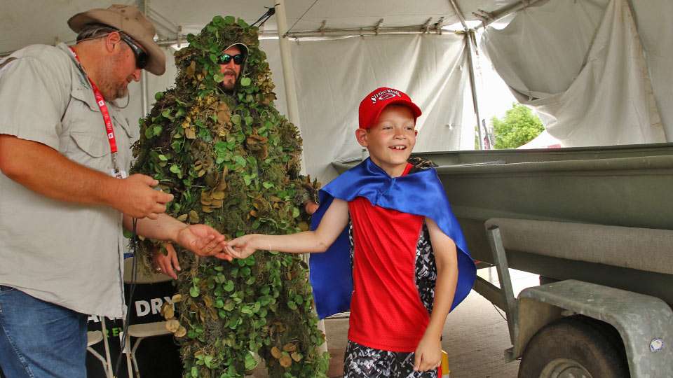 Colton Harbough, 7, of Prosper, gets a workout at the Clean, Drain and Dry tent. Wearing an Aquatic Invader Fighter! cape, he was given the task of finding mussels hidden in the boat. John Tibbs and John Findeisen (Giant Salvinia Monster) provide some clues.