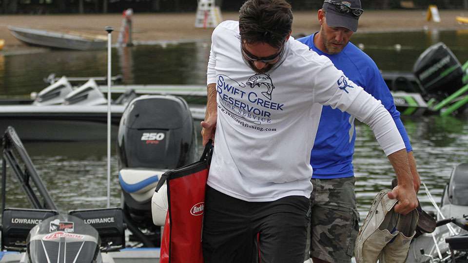With shoes and weigh-in bag in hand, Charlie Machek steps from his boat to the dock.