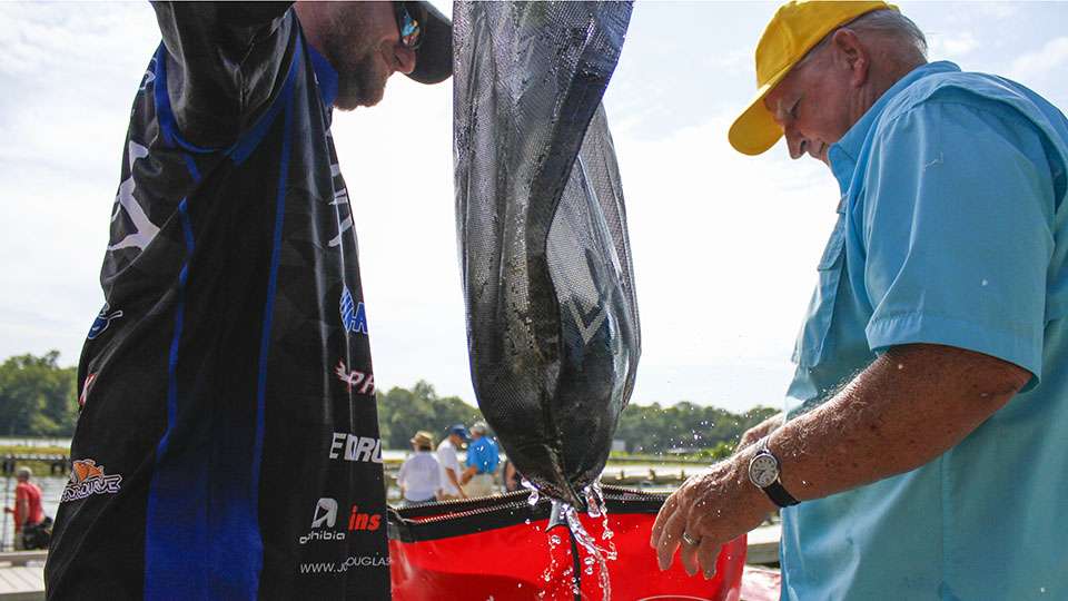 Josh Douglas takes his mesh weigh-in bag from the water and to the Bassmaster oxygenated tanks.