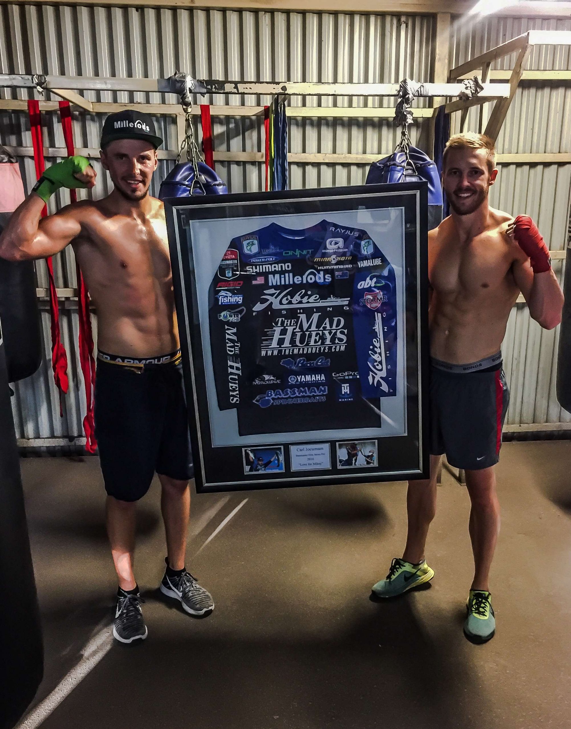 Jocumsen and George holding the framed jersey that will be auctioned live during their respective boxing matches. 
