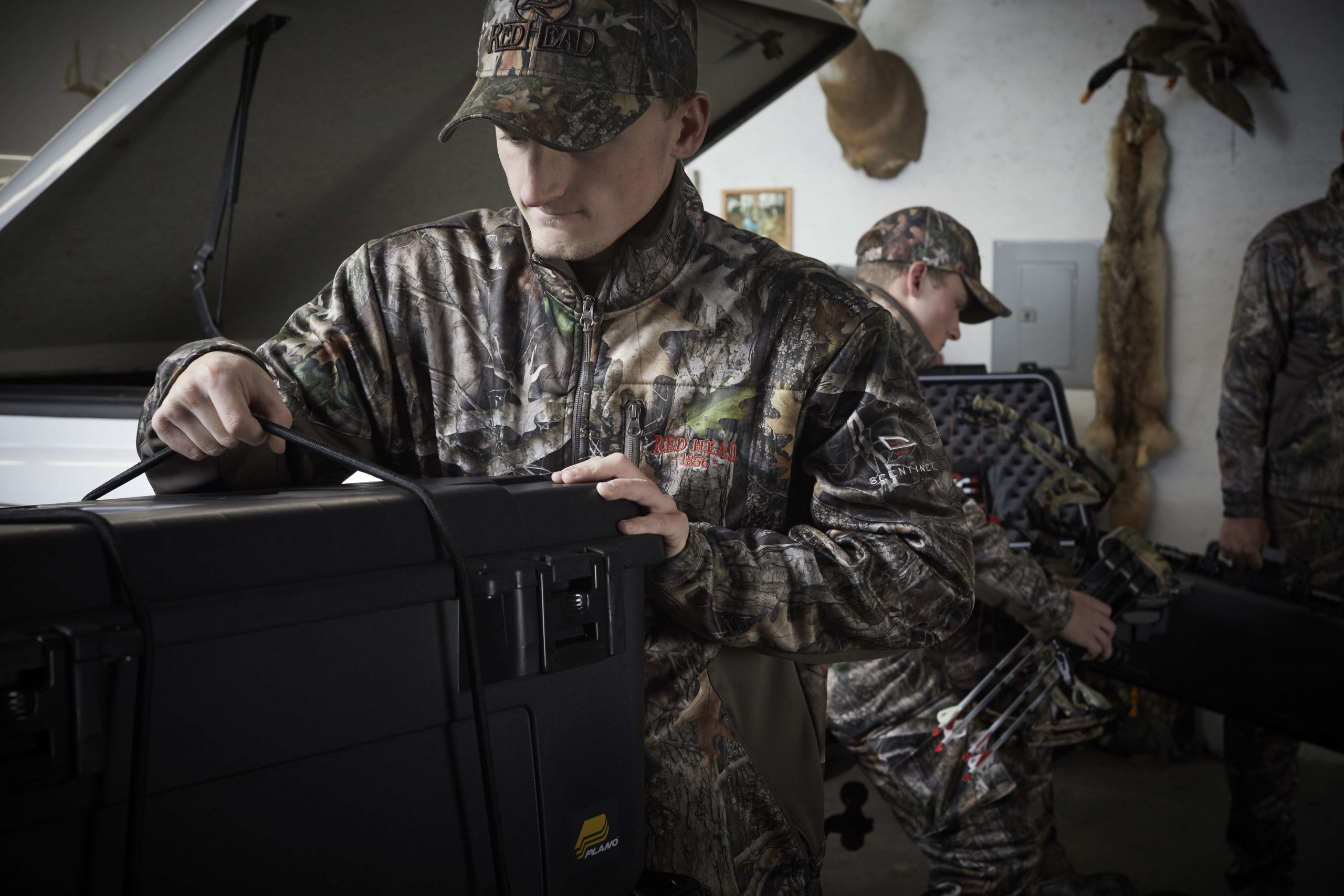 Jackson straps a Plano Sportsmans Trunk to the four-wheeler while Nicholas gets his bow ready; the amount of gear they take with them is staggering.