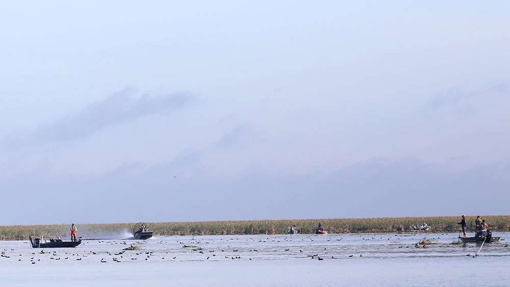 An airboat powers through a group of anglers ...