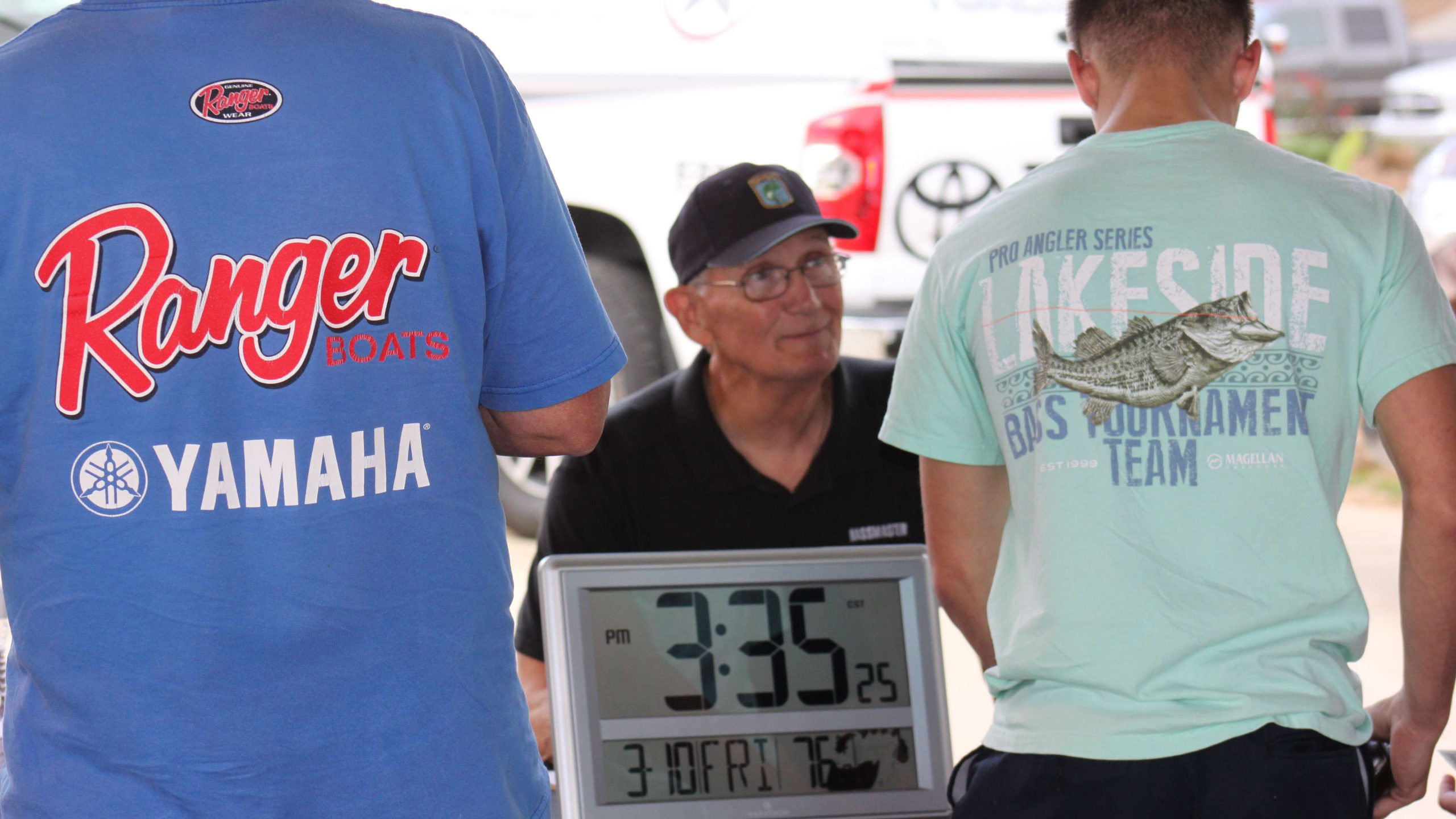 B.A.S.S. worker Ramon Quick talks with some of the anglers
registering on Friday. The ever-present B.A.S.S. clock tells date,
time, and more.