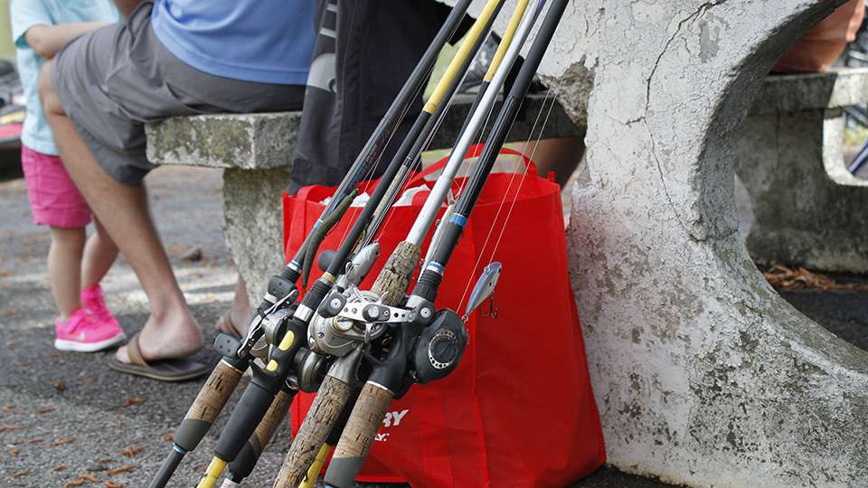 A co-angler puts his rods off to the side after unloading them from the boat.
