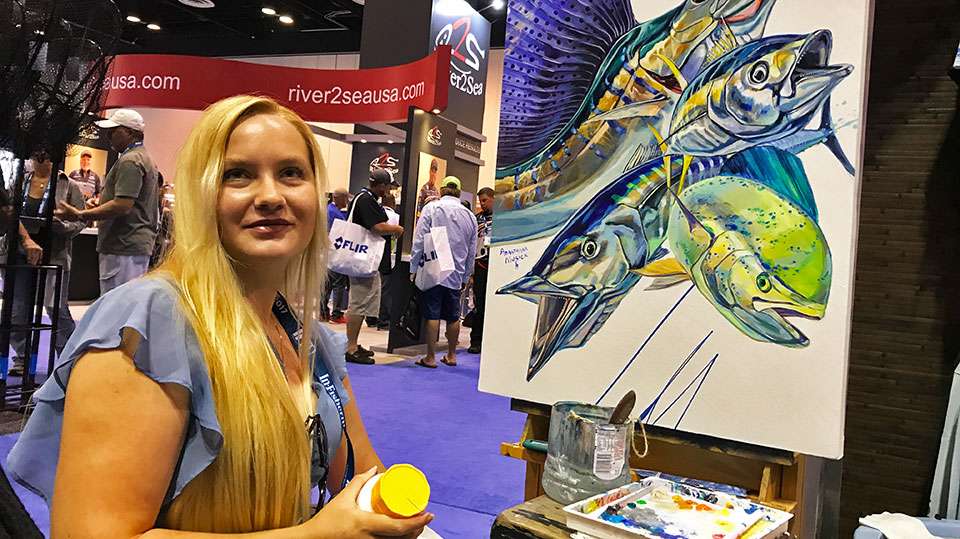Booths try to draw interest any way they can. Here fish artist Anastasia Musick paints to bring people into a saltwater display.