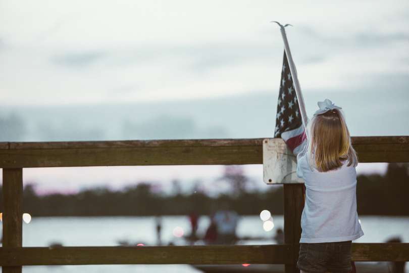 Day 1 of the Bassmaster Central Open on the Sabine River is about to kick off as a young fan holds the American flag for the playing of the National Anthem. 