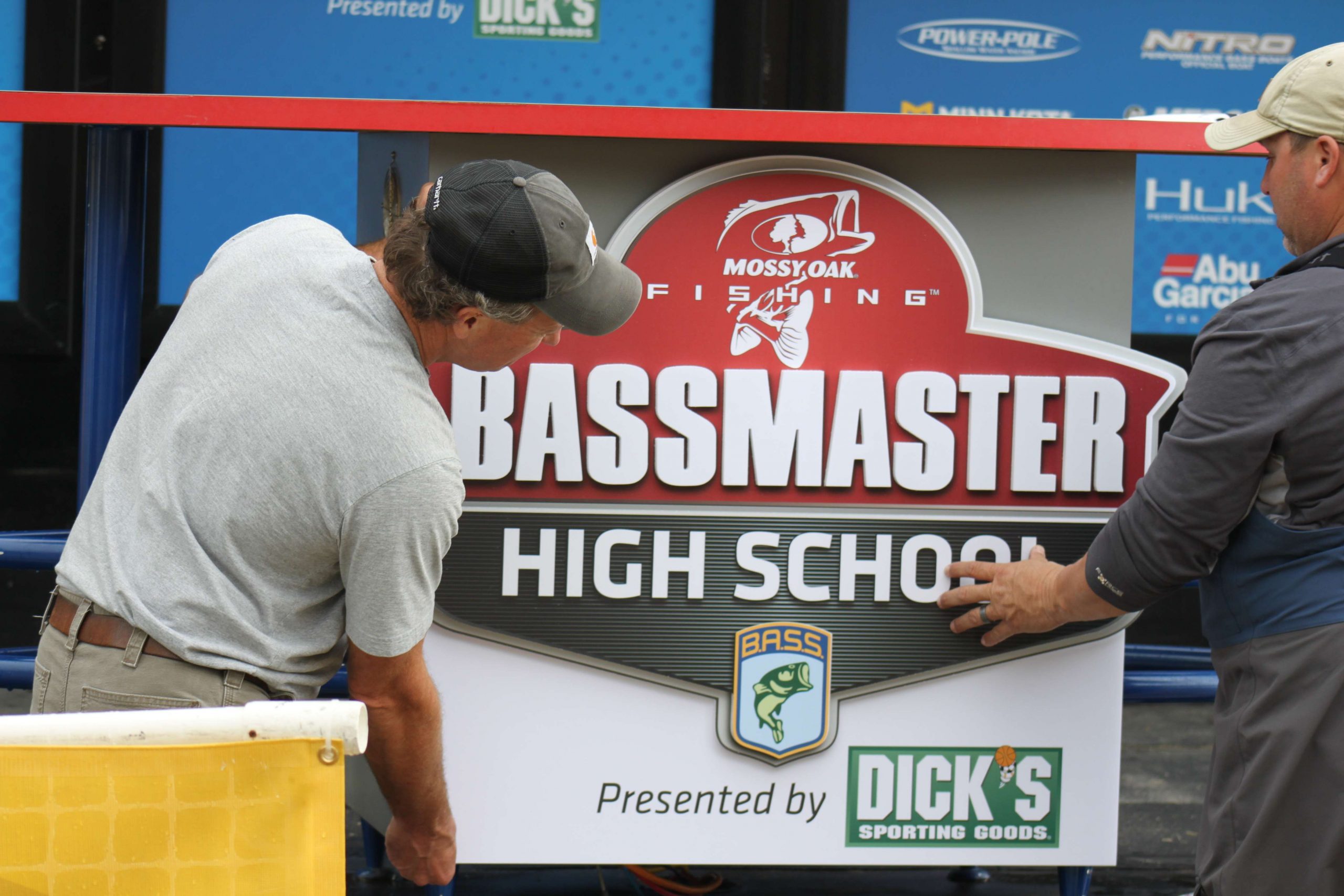BASS staff hang the new Mossy Oak Bassmaster High school sign on the BASS stage.