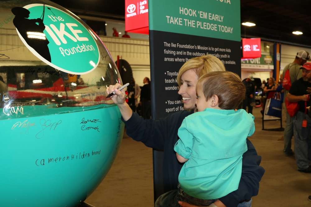 By signing the pledge float at The Ike Foundation booth, Dalena Hall promises her family will take 3-year-old Jaron fishing.