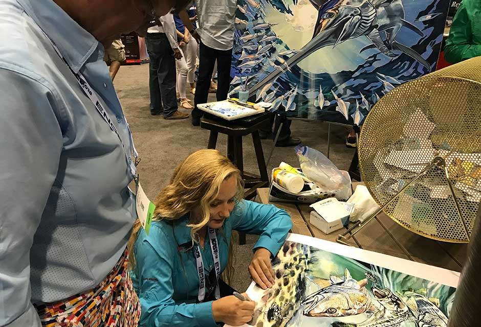 Artist Anastasia Musick drew a line at the Coastal Conservation Association of Florida booth as she worked on the painting (background) there then handed out signed art.