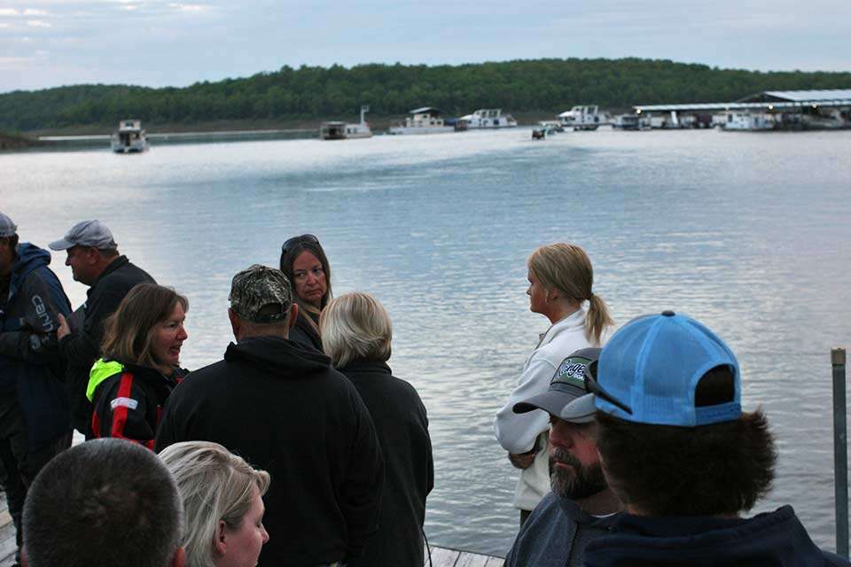 The parents and friends mingle at the dock as the final boats idle out of sight.