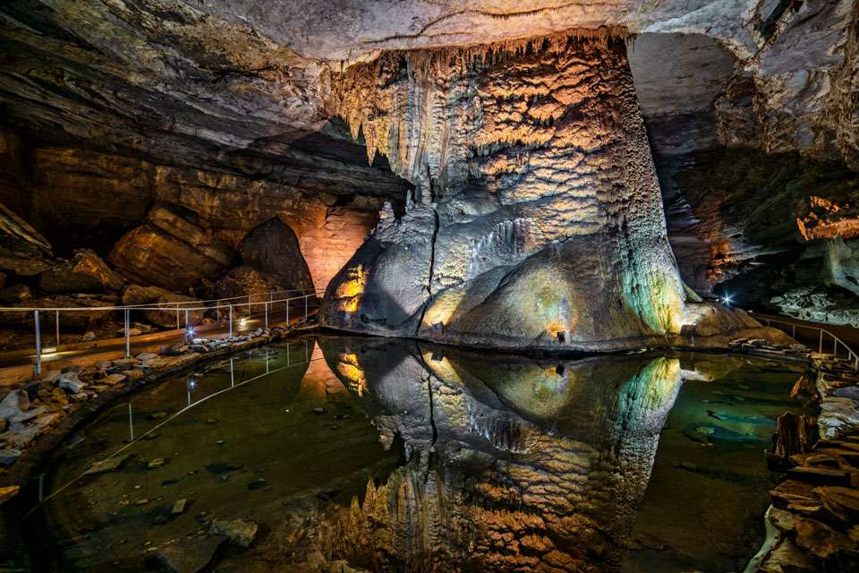Goliath is a massive stalagmite column standing on the edge of a pool of crystal-clear water. The reflection in the dim light makes it look like Goliath extends far below the surface of the water, which is actually only inches deep. The column stands 40 feet high and measures 240 feet around the base.