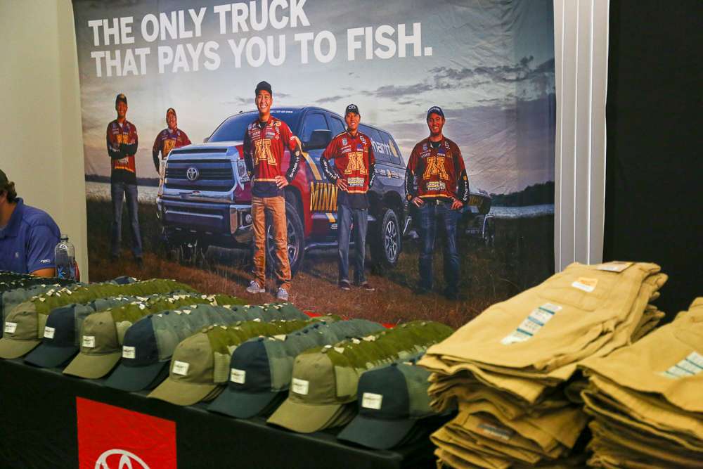 The picture of Bassmaster Classic competitor, Trevor Lo looks over the Carhartt hats to be given away. 