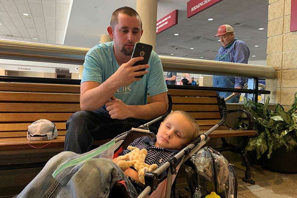 Justin Henderson of Hopkinsville, Ky., catches up on his phone while son, Brantley, 2, recharges. (He was later seen running around the weigh-in arena.) âThis is my first one,â said Henderson, whose brother was shopping. âI love it. Weâve been here three days. Itâs his nap time.â