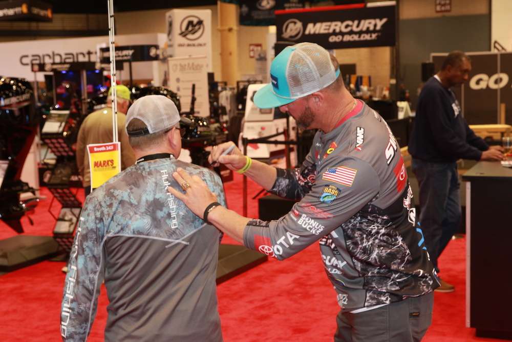Two-time Bassmaster Angler of the Year Gerald Swindle signs a fanâs shirt. 