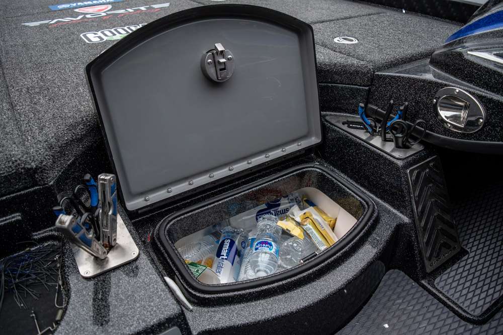 A cooler is located next to the console of the boat. This is the compartment he uses for cold items while fishing. 