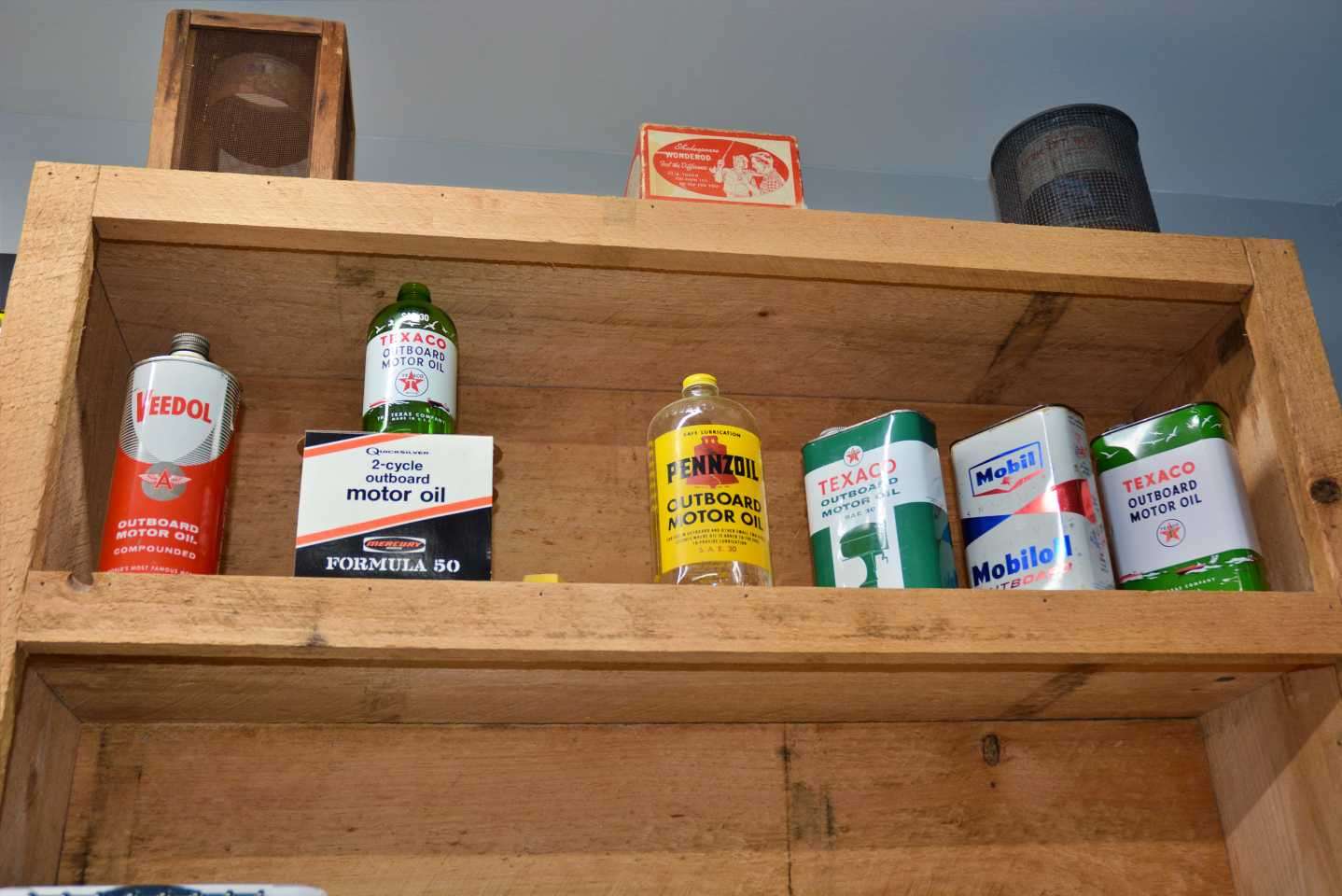 Gross' love for vintage marine collectibles includes outboard motor oil cans and containers. These are lined up on the upper shelves. The finds came from antique shops as well. 