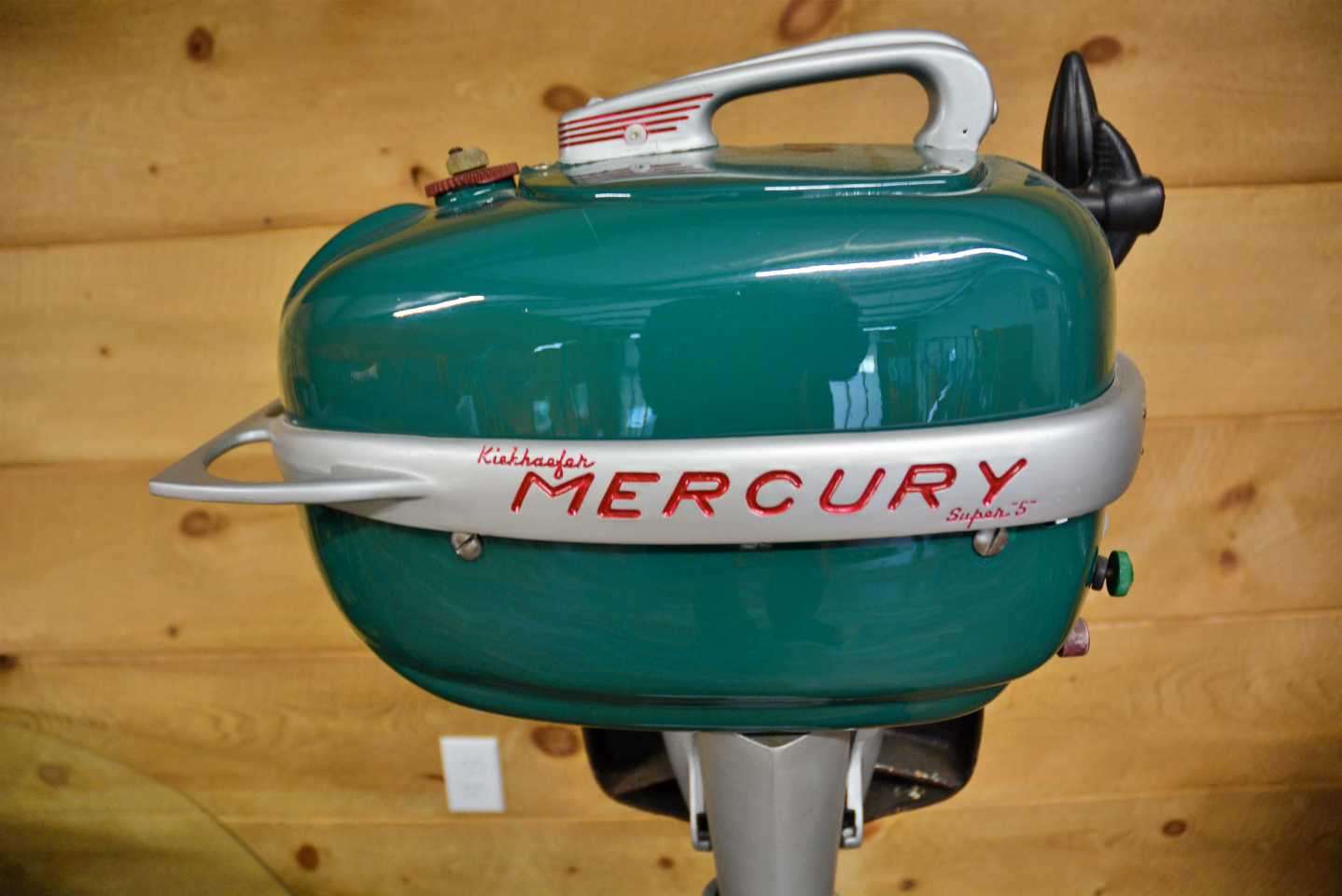 On the stand is a 1940s-era Kiekhaefer Mercury âSuper 5â outboard motor. 
