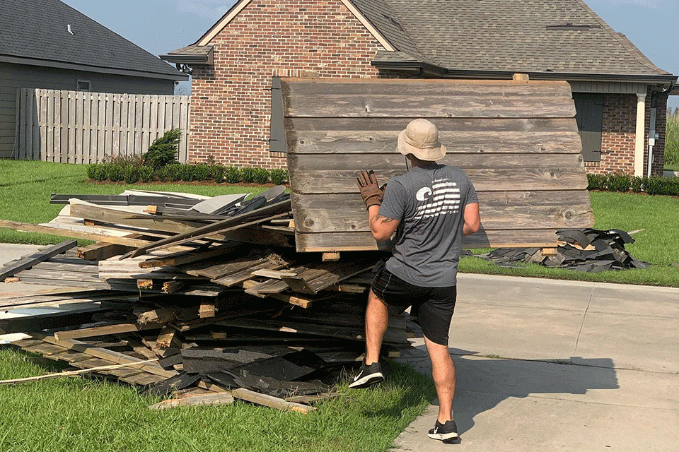 At his house nearby, Rivet piles up his blown down fence for removal. Two weeks after Ida, there were piles of debris on almost every street as the long cleanup was just getting under way.