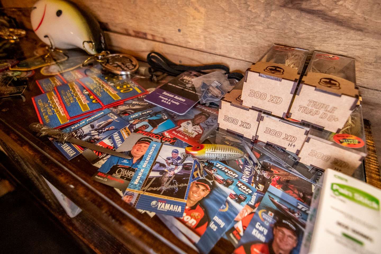 The top of the bookshelf is another glass case. It holds signed angler cards, tournament trail patches and more. During that time, Yamaha and Mercury made cards for the anglers to sign and hand out to fans.  