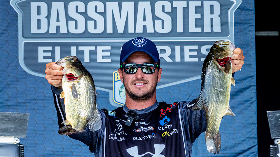 Chris Johnston holds two giant bass on the Bassmaster weigh-in stage.